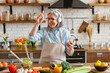 © InsideCreativeHouse - Happy mature woman dance and cook in the kitchen, listen popular track, having fun, moving to favorite music while prepare healthy dieting vegetarian salad at home. Chore, lifestyle, weekend activity