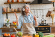 © InsideCreativeHouse - Kitchen, woman and dancing with headphones in home for break, music playlist or streaming radio. Dancer, retired person and fun with album track, listening to audio or media podcast with energy