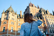 © Erik Naumann/Stocksy - Woman with denim jacket taking a photo of Chateau Frontenac