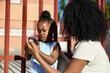 © Edu Bastidas + David Garcia/Stocksy - Mother showing daughter something on phone before school