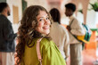© J Esteban Berrío/Stocksy - Female student smiling looking back at campus hallway