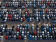 © AmazingAerialAgency - Aerial view of a sea of orderly parked cars, where vibrant reds, whites, blues, and blacks create a stunning mosaic of automotive colors, Civitavecchia, Lazio, Italy.