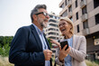 © Nenad - Smiling businesswoman and businessman standing on the street Beautiful businesswoman talking with her colleague