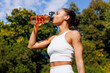 © Artem Podrez/Stocksy - Woman drinking water from bottle after outdoor workout