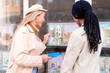 © Iryna - Two women look at house listings on display outside a real estate office in the afternoon