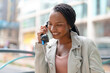 © Iryna - Woman talking on a phone in a city street during daytime while smiling and enjoying the conversation
