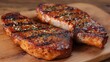 © mila103 - Grilled pork chops on wooden board with seasoning and herbs.