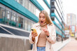 © Iryna - Woman surprises herself while looking at her phone on a city street in the daytime