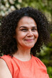 © ByLorena/Stocksy - Smiling Woman With Curly Hair Wearing Orange in Natural Setting