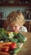 © spyrakot - Young child with head lowered near fresh vegetables on wooden table in warm kitchen