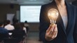 © Tantri - A professional holds a glowing light bulb featuring a brain A blurred audience and presentation screen are visible in the background