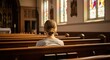 © Sadek - A woman sits alone in a church with stained glass windows and wooden pews.
