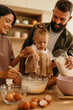 © La Famiglia - Happy family baking together, adding flour to dough