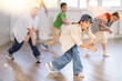 © JackF - Emotional tween girl mastering krump dance routines during lively group session in children dance studio, guided by passionate male teacher..