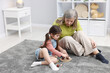 © New Africa - Nanny and cute little girl playing with wooden pieces on floor indoors, space for text