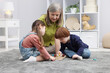 © New Africa - Nanny and cute little kids playing with wooden pieces on floor indoors