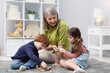 © New Africa - Nanny and cute little kids playing with wooden pieces on floor indoors