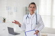 © New Africa - Portrait of smiling cardiologist with clipboard and pen in clinic