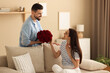© New Africa - Man greeting his girlfriend with beautiful bouquet at home