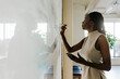 © BONNINSTUDIO/Stocksy - Woman writing on whiteboard during presentation at office