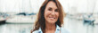 © Andrii Nekrasov - Close up, happy attractive middle age woman standing in port on yacht background looking at camera with smile. Panoramic