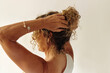 © Eliza Alves/Stocksy - Back view of a mature woman with toned arms and curly hair