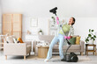 © Pixel-Shot - Young woman with vacuum cleaner singing at home