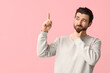 © Pixel-Shot - Thoughtful young man pointing up on pink background