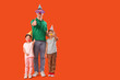© Pixel-Shot - Father and his little children with funny disguises showing thumbs-up on orange background. April Fool's Day celebration