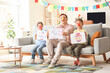 © Pixel-Shot - Father and his children with April Fool's Day posters at home
