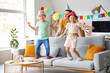 © Pixel-Shot - Father and his children with party hats having fun at home. April Fool's Day celebration