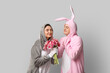 © Pixel-Shot - Beautiful young couple in bunny costume with bouquet of tulips on grey background. Easter celebration