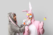 © Pixel-Shot - Beautiful young couple in bunny costume with paper Easter eggs on grey background