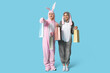 © Pixel-Shot - Beautiful young couple in bunny costume with shopping bags on blue background. Easter celebration