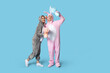 © Pixel-Shot - Beautiful young couple in bunny costume with Easter egg and gifts on blue background