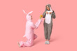 © Pixel-Shot - Beautiful young couple in bunny costume with bouquet of tulips on pink background. Easter celebration