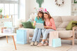 © Pixel-Shot - Happy young women in bunny ears headbands with laptop and paper bags at home. Online shopping for Easter