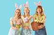 © Pixel-Shot - Young girls with Easter bunny ears, baskets and eggs on blue background