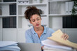 © Kawee - Latina businesswoman working and reviewing documents on desk at office.