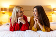 © Graphicroyalty - Two beautiful young women lying on a bed laughing together. Friendship, happiness and lifestyle concept. Cheerful female friends or lesbian couple sharing a joyful moment in a cozy hotel bedroom