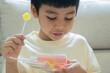 © Kunlathida - Adorable Asian little boy enjoying shiny yellow lollipop and colorful candies