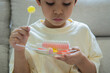 © Kunlathida - A young Asian boy holds a plate of vibrant, colorful candies with excitement