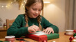 © VectorVille - Young girl wrapping gift and attaching card at table during holidays
