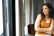 © Wavebreak Media - African American woman wearing rust orange tank top, standing at home by sliding door, copy space