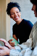 © we.bond.creations - Happy black woman holding a notebook and smiling while listening to a colleague during a professional business meeting