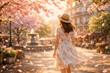 © Kathy - Elegant woman in floral dress walking through sunlit city square with cherry blossoms and fountain. Romantic spring atmosphere with soft golden light.