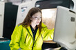 © eakgrungenerd - Female industrial engineer wearing safety jacket and protective goggles operating CNC machine in modern factory, focused on quality control, automation process, advanced manufacturing technology.