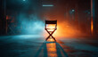 © Sher - an empty film director's chair stands in the center of an industrial warehouse, illuminated by spotlights and surrounded by smoke.