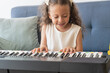 © Hector Pertuz - Young girl learning keyboard playing for education hobby