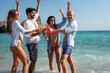 © NDABCREATIVITY - Group of young friends having fun at the beach with colorful drinks, laughing in the sun at summer